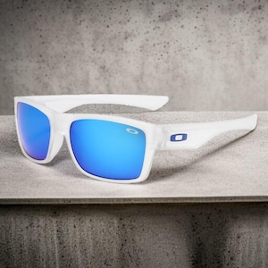May include: White sunglasses with blue mirrored lenses. The sunglasses have a rectangular frame and a white arm with a blue logo. The lenses reflect a bright blue color.