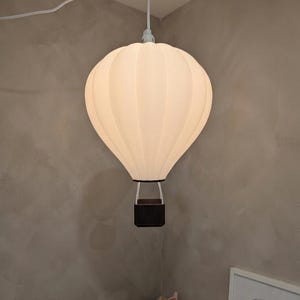 Könnte beinhalten: Ein Set aus drei Keramikbechern mit gesprenkelter, matter Oberfläche. Die Becher sind in Creme-, Hellgrau- und Dunkelgrautönen gehalten. Jeder Becher hat ein schlichtes, minimalistisches Design und einen abgerundeten Henkel.