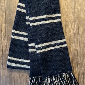 May include: Black and white striped knitted scarf with fringe tassels.