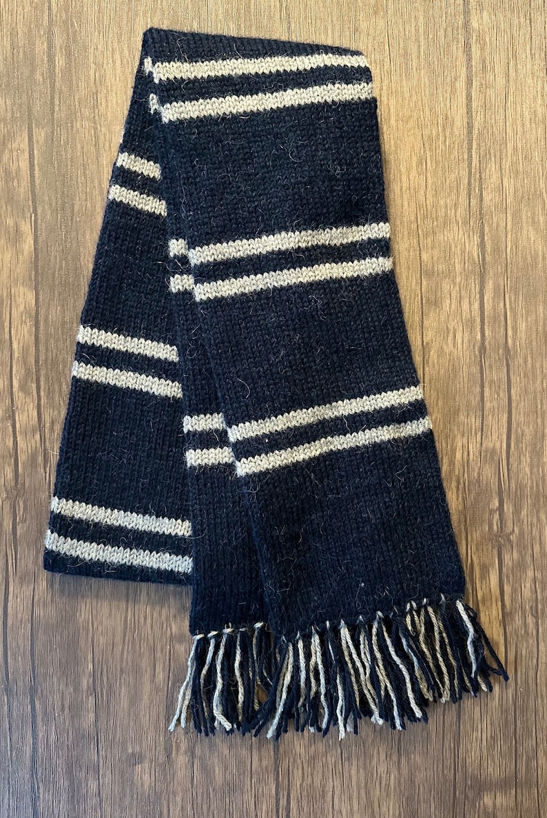 May include: Black and white striped knitted scarf with fringe tassels.