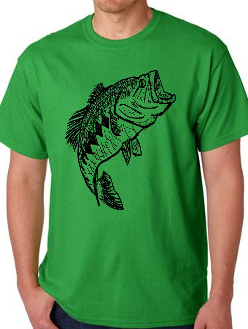 Pu&ograve; includere: Una maglietta verde con un disegno a linea nera di un pesce persico che salta fuori dall'acqua.
