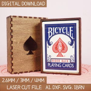 Puede incluir: Una caja de madera para naipes con un diseño de pica cortado con láser. La caja contiene una baraja de naipes Bicycle Rider Back. El texto "DESCARGA DIGITAL" y "ARCHIVO DE CORTE LÁSER" son visibles.