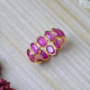 Anillo ovalado de rubí con banda de eternidad en oro de 14 quilates para mujer.