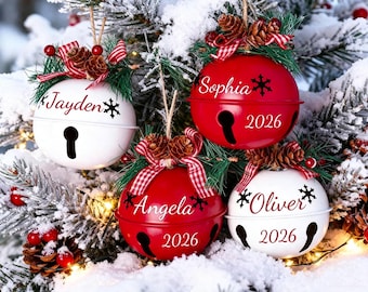 May include: Four round metal jingle bell ornaments in red and white, each personalised with names like Jayden, Sophia, Angela, and Oliver, plus the year 2026. Each bell features a pinecone, green needles, and a red and white checkered ribbon.