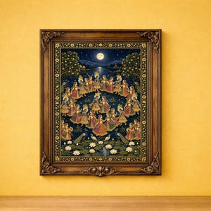 May include: A framed wall art print depicting a circular dance of figures in colorful traditional attire under a full moon. The scene features a dark blue night sky, lush trees, white lotus flowers, and peacocks in a detailed decorative border.