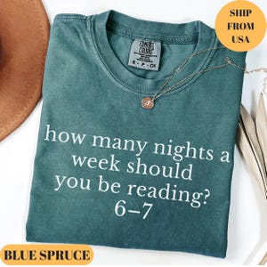 Puede incluir: Una camiseta azul verdoso con el texto "how many nights a week should you be reading? 6-7" en blanco. La camiseta tiene cuello redondo y mangas cortas. Un collar dorado con un colgante est&aacute; sobre la camiseta.