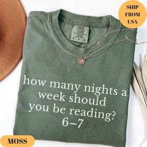 Puede incluir: Una camiseta verde musgo con el texto "how many nights a week should you be reading? 6-7" en blanco. La camiseta tiene cuello redondo y mangas cortas. Un collar dorado con un colgante est&aacute; sobre la camiseta.
