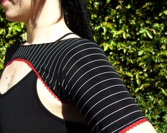 May include: Black top with a unique design featuring a cutout and striped sleeves. The sleeves are black with white stripes and red trim. The top is a stylish piece of clothing.
