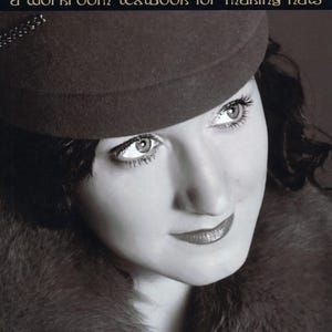 May include: A book cover titled Vintage Millinery: a workroom textbook for making hats. The cover features a black and white portrait of a person wearing a dark felt hat with a decorative trim and a fur collar, set against a dark background.