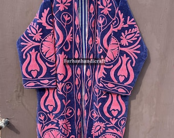 May include: A long, navy blue coat with intricate pink floral embroidery. The coat features a high collar and long sleeves. The interior lining is striped in blue and white. The coat is hanging on a wooden hanger.