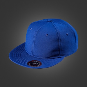 Könnte beinhalten: Königsblaue Baseballkappe mit flachem Schirm. Die Kappe hat eine strukturierte Krone mit sechs Einsätzen und einen kleinen, kreisförmigen Aufnäher an der Seite. Der Aufnäher hat weißen Text auf schwarzem Hintergrund.