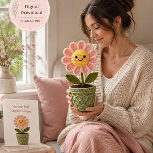 Può includere: Uno schema all'uncinetto per un vaso di fiori con una margherita gialla e rosa sorridente con foglie verdi in un vaso verde testurizzato. Il download digitale include un PDF stampabile con il testo Flower Pot Crochet Pattern e un'immagine.