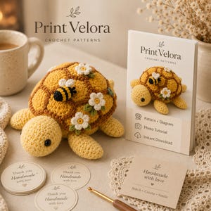 May include: A yellow crocheted turtle toy with a brown shell, decorated with white flowers and a small bee. Beside it is a Print Velora crochet pattern booklet, three circular thank you tags, and a square card reading Handmade with love.