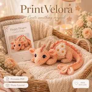 Puede incluir: Un juguete de dragón tejido a ganchillo de color melocotón con alas blancas con patrón de margaritas y cuernos color canela, junto a un folleto titulado Floppy Dragon Crochet Pattern. El folleto incluye instrucciones y tutoriales.