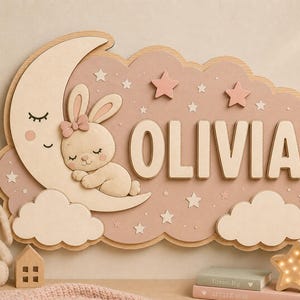 May include: A wall-mounted wooden sign featuring a sleeping rabbit on a crescent moon, clouds, and stars in soft pink and cream tones. The name OLIVIA is displayed in large, raised, cream-colored capital letters against a dusty pink cloud background.
