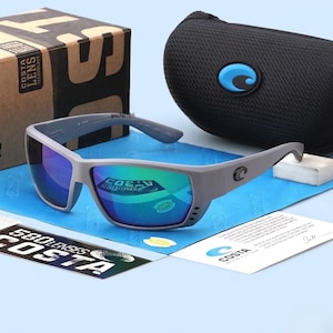 May include: Gray sunglasses with blue and green reflective lenses, a black case with a blue logo, and a cardboard box. The sunglasses have the brand name "Costa" on the frame and lenses.