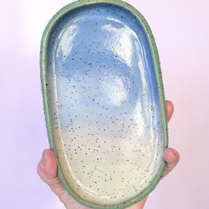 Pu&ograve; includere: Vassoio ovale in ceramica fatto a mano con interno blu e bianco maculato e bordo verde. Il vassoio misura circa 20 cm di lunghezza e 10 cm di larghezza, ideale per contenere gioielli o piccoli oggetti.