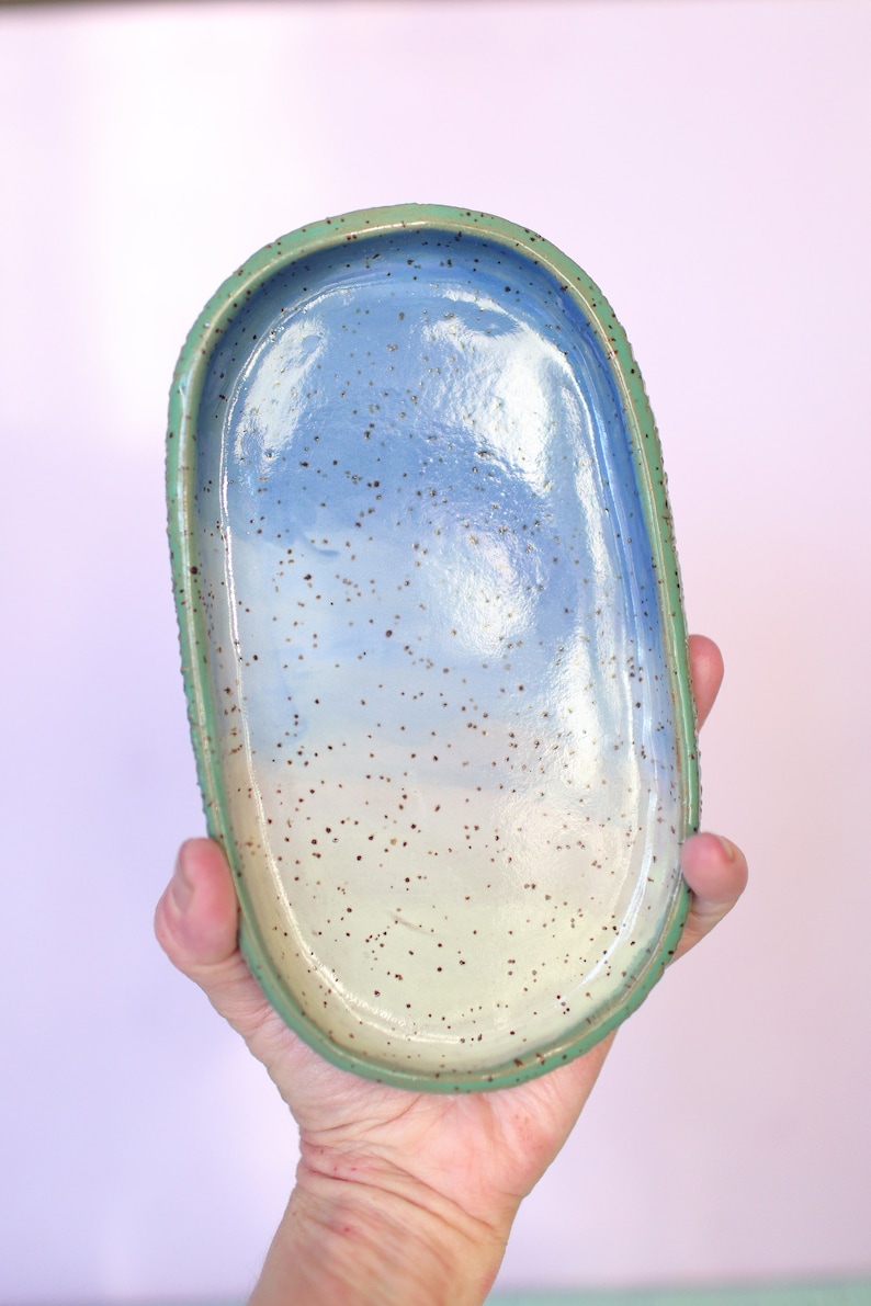 Pu&ograve; includere: Vassoio ovale in ceramica fatto a mano con interno blu e bianco maculato e bordo verde. Il vassoio misura circa 20 cm di lunghezza e 10 cm di larghezza, ideale per contenere gioielli o piccoli oggetti.