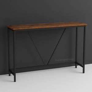 Op de afbeelding: Een moderne consoletafel met een donkerbruin houten blad en een zwart metalen frame. De tafel heeft een geometrisch ontwerp op het voorpaneel en is geschikt voor entrees of woonkamers. TheDesignshoop.