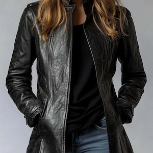 May include: A black leather jacket with a stand-up collar and a zipper closure. The jacket has long sleeves and pockets. The jacket is worn over a black top and blue jeans.