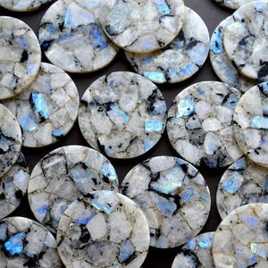 Op de afbeelding: Een verzameling ronde, gepolijste edelsteen onderzetters. Elke onderzetter heeft een mozaïekpatroon van witte, zwarte en blauw getinte stenen. De onderzetters hebben een diameter van ongeveer 10 cm en tonen een natuurlijke, elegante esthetiek.