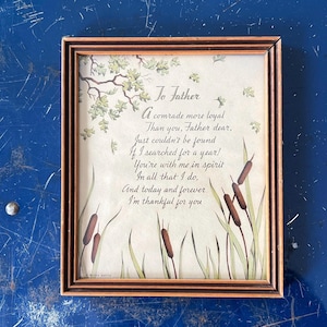 Könnte beinhalten: Ein gerahmter Druck mit einem braunen Holzrahmen. Der Druck zeigt ein Gedicht mit den Worten "To Father" oben, zusammen mit Illustrationen von Schilf, Blättern und Zweigen. Der Hintergrund ist hellbeige.
