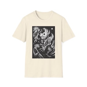 May include: A cream-coloured t-shirt displaying a black and white cartoon monster illustration. The monster has large eyes, a long tongue, and sharp teeth, set against a dark background with a moon.