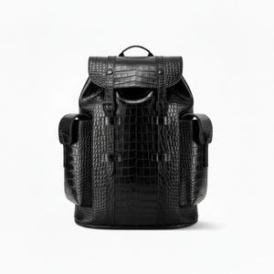 Puede incluir: Mochila negra con un patrón texturizado similar a la piel de cocodrilo. Cuenta con cierre de solapa con hebillas, asa superior y dos bolsillos laterales. Diseño elegante y moderno.