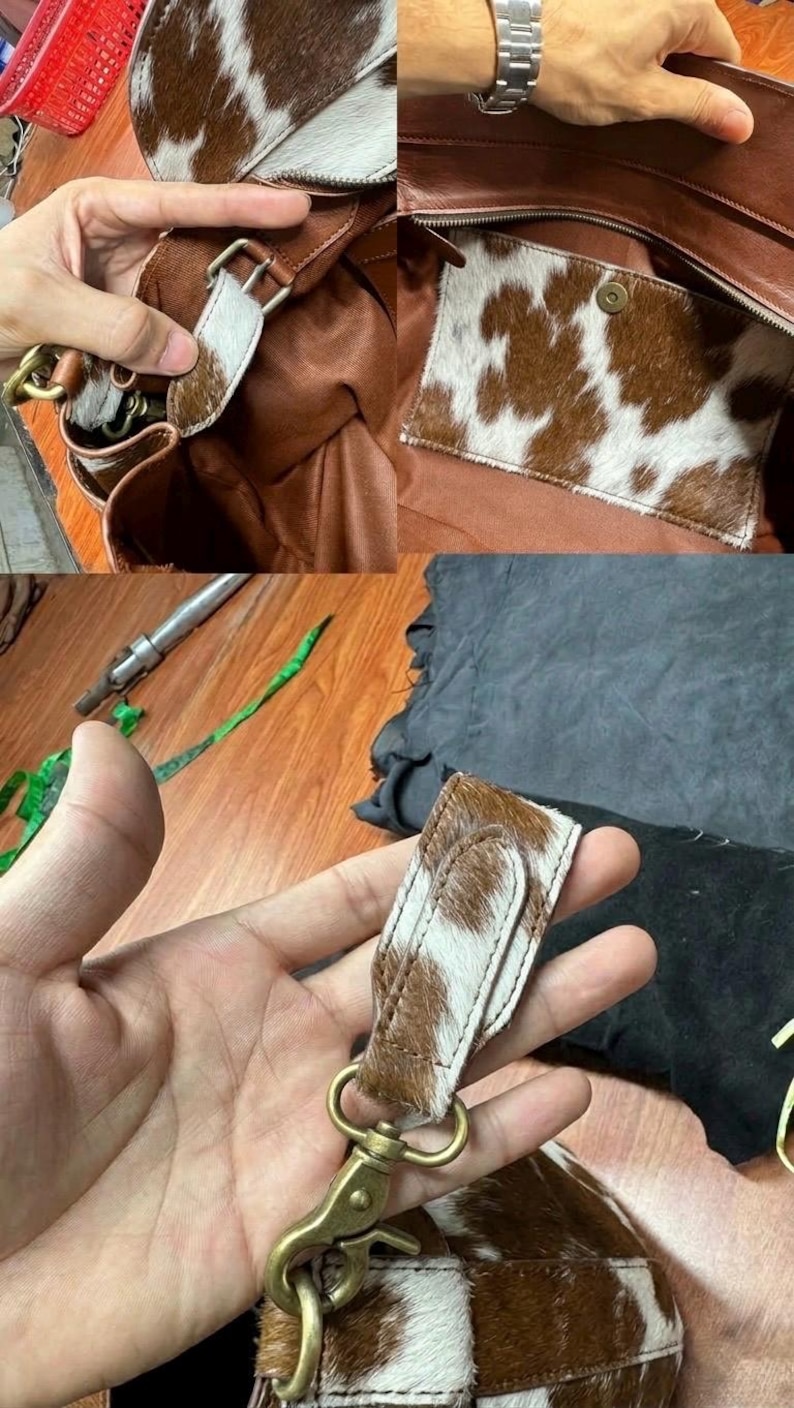 Op de afbeelding: Een bruine leren handtas met een koeienhuidpatroon. De tas heeft een ritssluiting, een binnenvak en een afneembare riem met een messing sluiting. Het koeienhuidpatroon is bruin en wit.
