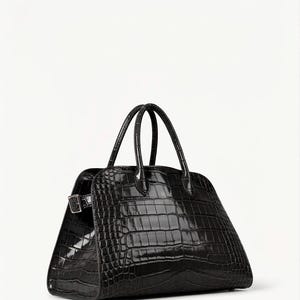 Puede incluir: Un bolso negro estructurado con textura brillante de piel de cocodrilo. Cuenta con dos asas superiores redondeadas y un cierre de hebilla plateada. La forma trapezoidal y el acabado brillante le dan un aspecto lujoso.