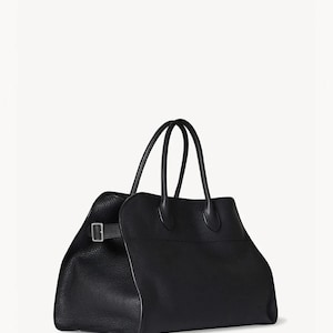 May include: A black leather tote bag with two top handles and a rectangular shape. The bag features a buckle closure on the side and a textured surface. The bag is designed for carrying items.