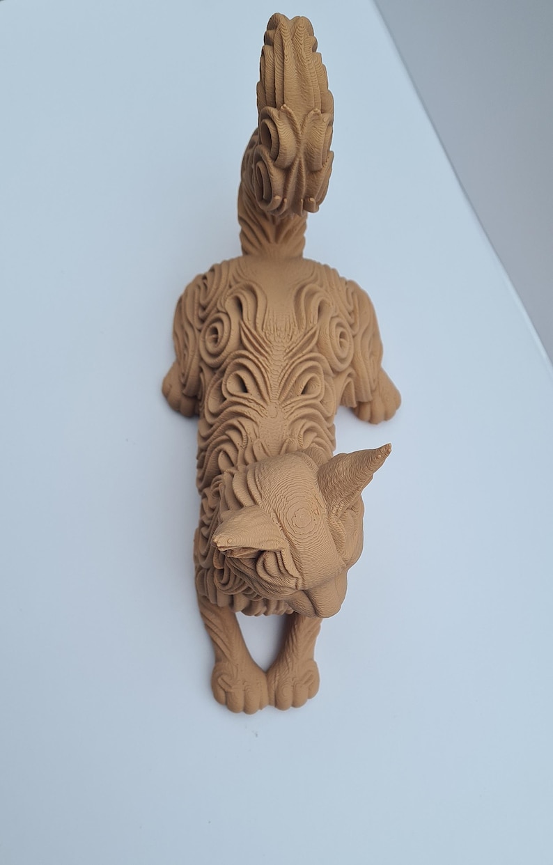 Op de afbeelding: Gedetailleerde, bruine sculptuur van een gestileerd dier, mogelijk een kat of hond, met ingewikkelde gesneden patronen. De sculptuur heeft een prominente staart en een gedetailleerd gezicht, dat een uniek artistiek ontwerp laat zien.
