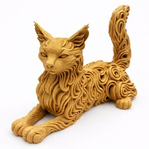 Op de afbeelding: Een gedetailleerde, goudkleurige kattenbeeldhouwwerk in een ontspannen pose. De vacht van de kat is ingewikkeld ontworpen met wervelende patronen. De sculptuur heeft spitse oren en een lange, gekrulde staart, rustend op een witte ondergrond.