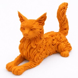 Op de afbeelding: Oranje kattenbeeld met gedetailleerde vacht en gekrulde staart. De kat ligt in een liggende houding, met uitgestrekte poten. Het beeld is gemaakt van een textuurrijk materiaal en heeft een gestileerd ontwerp. Het kattenbeeldje is een decoratief item.
