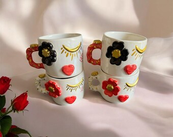気まぐれな花の顔のマグカップ | 手作りの陶器のカップに彫刻された顔 