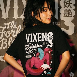 Può includere: T-shirt nera con grafica di una figura simile a una volpe con un ventaglio, con le scritte "VIXEN" e "The Forbidden Bloom issue". Include caratteri giapponesi, la scritta "NSFW!" e "May 2024".