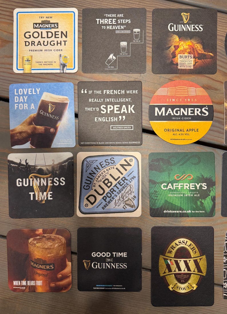 Op de afbeelding: Een verzameling vierkante en ronde drankonderzetters met logo's en teksten van Ierse merken. De onderzetters tonen logo's, teksten en afbeeldingen, waaronder het Guinness-logo en het Magners-logo.