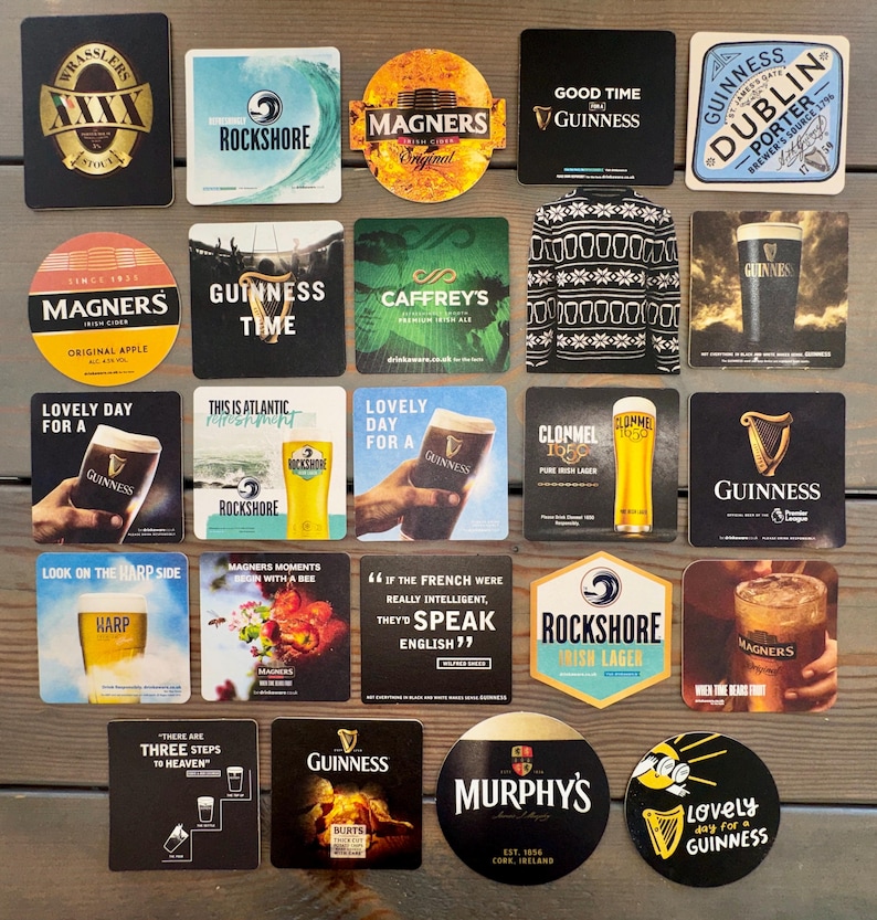 Op de afbeelding: Een verzameling bier- en cideronderzetters met verschillende logo's en tekst. Merken zijn onder andere Guinness, Magners, Rockshore en Harp. Sommige onderzetters tonen zinnen als "Lovely Day for a Guinness" en "Good Time Guinness."