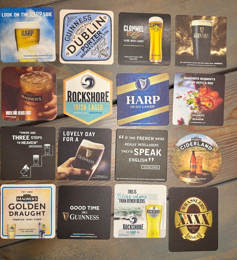Puede incluir: Un conjunto de posavasos de cerveza y sidra con marcas como Guinness, Harp y Magners. Los posavasos muestran im&aacute;genes de bebidas, logotipos y texto, con varias formas y dise&ntilde;os. Los posavasos est&aacute;n sobre una superficie de madera.