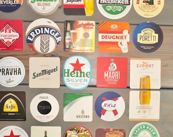Peut inclure: Un ensemble de dessous de verre de bière avec des logos de différentes marques. Les dessous de verre sont de formes variées, rondes, carrées et rectangulaires. Les couleurs sont diverses, avec une utilisation importante de rouge, vert et blanc. Certains présentent du texte et des illustrations.