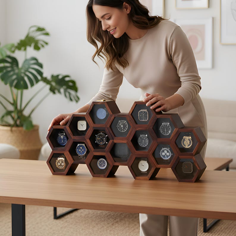 May include: Wall-mounted wooden watch box with a honeycomb design. The box is made of light and dark wood and displays several watches. The text "Wall Mounted Wooden Watch Box" is above the box.
