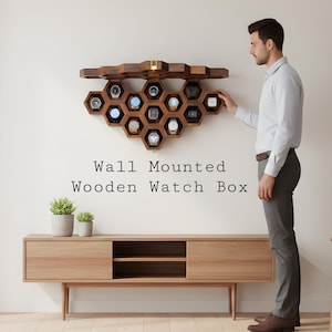 May include: A wall-mounted wooden watch box with a honeycomb design, holding multiple watches. The box is made of dark wood and is mounted on a white wall. The text "Wall Mounted Wooden Watch Box" is displayed below the watch box.