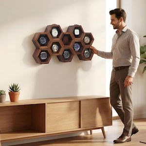 May include: Wall-mounted wooden watch box with a honeycomb design. The box is made of light and dark wood and displays several watches. The text "Wall Mounted Wooden Watch Box" is above the box.