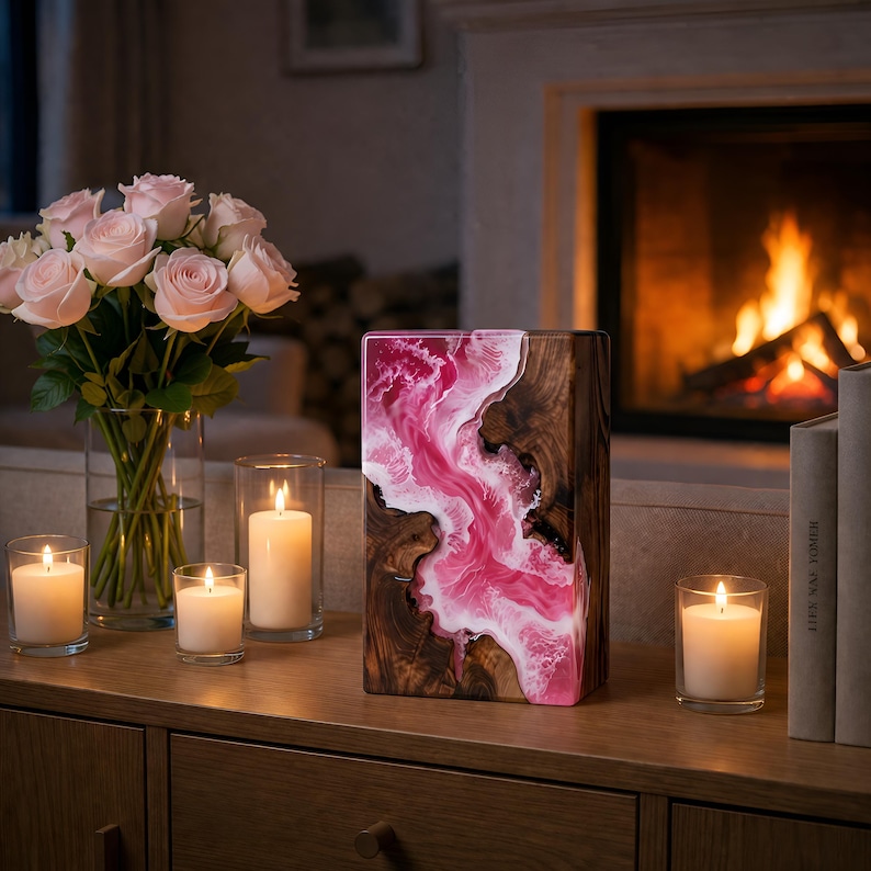 May include: A decorative wooden block with a pink and white resin design. The block is on a wooden surface with lit candles and a bouquet of pink roses. A fireplace is in the background.