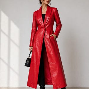 May include: A long, vibrant red leather coat with a tailored fit. The coat features a notched lapel, a single-button closure, and front pockets. The coat is worn with black pants and boots, and a small black handbag.