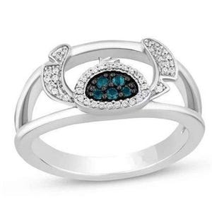 Op de afbeelding: Een zilveren ring met een centraal ontwerp van teal-kleurige stenen omringd door kleine witte stenen. De ring heeft een split-schacht ontwerp met extra witte stenen aan de zijkanten.