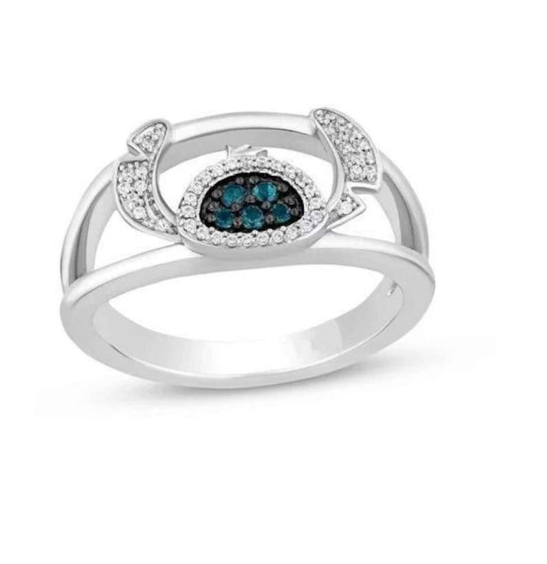 Op de afbeelding: Een zilveren ring met een centraal ontwerp van teal-kleurige stenen omringd door kleine witte stenen. De ring heeft een split-schacht ontwerp met extra witte stenen aan de zijkanten.