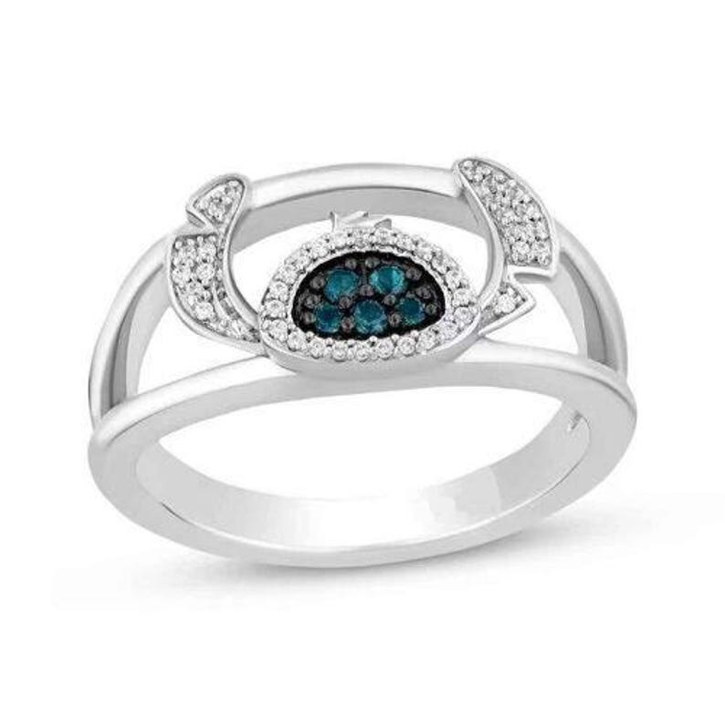 Op de afbeelding: Een zilveren ring met een hoefijzerontwerp. Het middenstuk heeft een cluster van blauwe edelstenen, omgeven door een halo van witte edelstenen. Extra witte edelstenen zijn langs de hoefijzervormige rondingen gezet.