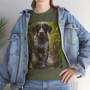 Op de afbeelding: Olijfgroen T-shirt met een Duitse Staande Hond die door riet rent. De hond heeft een gevlekte vacht en een rode halsband. De afbeelding is gedrukt op een groen t-shirt.