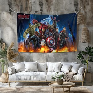 Puede incluir: Un gran tapiz con el equipo de los Vengadores de la película "Age of Ultron". La obra de arte representa a Hulk, Iron Man, Capitán América, Thor, Viuda Negra y otros contra un fondo de fuego. El logotipo de los Vengadores es visible en la parte superior.